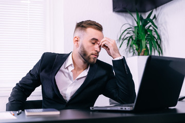 Feeling exhausted. Frustrated young beard man massaging his nose