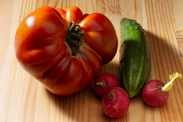 large red tomato cucumber and radish on a wooden background