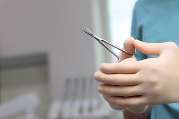 Dental tool scissors in the hands of a dentist. Unrecognizable photo without a face. Only hand. Copy of the space.
