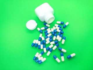 Pills isolated on a green background. Set of tablets in capsules.  A kit of medical pills for treatment. Pack of pills, capsules. Bottle with pills.