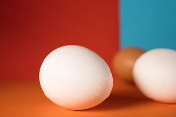 Farm white and brown chicken eggs, close-up and on a red-blue background