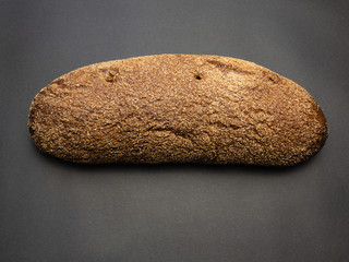 Bread isolated on a black background. Bread with bran. Long loaf isolated. A crust of bread.