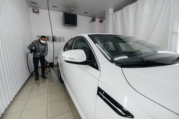 Modern washing with foam and high-pressure water of a white car. Car wash