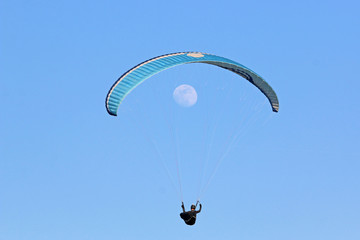 Paraglider flying wing in a blue sky with the moon
