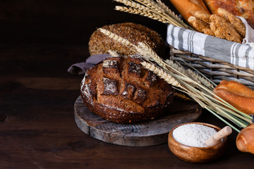 Concept of homemade bread, natural farm products, domestic production. Healthy and tasty organic food. Close up,  dark black background. Copy space for text