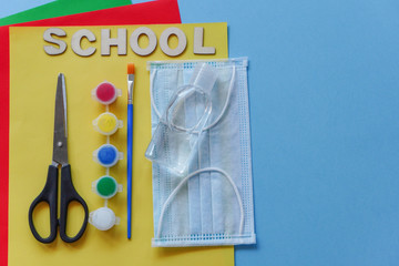 Study flatlay concept.Education supplies-pencil,pen,brush, paint, medical mask and sanitizer paint on blue background flatly,back to school or kindergarten. summertime, creativity and learn background