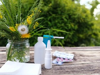 Wild flowers, nose spray, handkerchiefs, eye drops on wooden surfaces