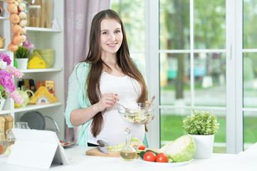 Beautiful pregnant young woman cooking in kitchen