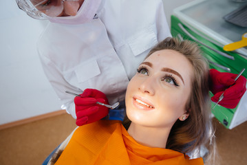 A professional dentist performs treatment and examination of the patient's oral cavity in close-up....