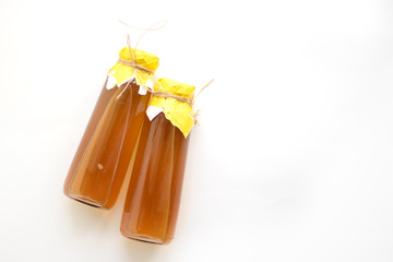 Refreshing filtered kombucha tea in a glass bottle. Fermented healthy drink for two, tied with...