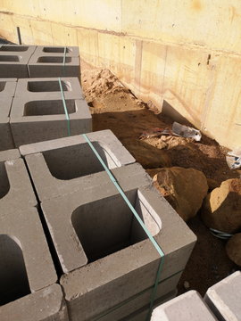 Graue Steine mit Winkelprofil als Baumaterial auf der Baustelle bei Sonnenschein mit Fassade in Beige im Rohbau in Oerlinghausen bei Bielefeld am Hermannsweg im Teutoburger Wald in Ostwestfalen-Lippe