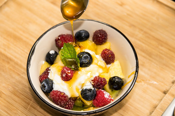 forest fruit cocktail in porcelain cup. A jet of honey falls on the fruits