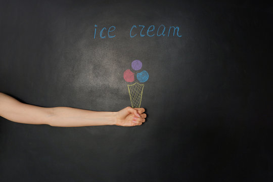 Ice cream cone in the hand. Bright chalk drawing on black chalkboard