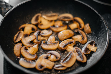 Thinly sliced fresh raw mushrooms are fried in a pan close-up. Healthy diet