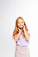Fototapeta premium cute red-haired girl in ordinary clothes touches her hair and smiles