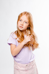 cute red-haired long-haired girl in daily clothes (skirt, T-shirt) braids her hair