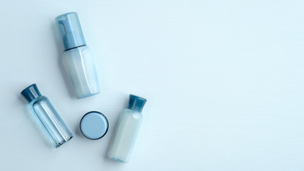 Set of natural organic SPA cosmetic products on blue background. Flat lay, top view transparent cosmetic bottles and cream jar. Banner mockup for beauty salon.