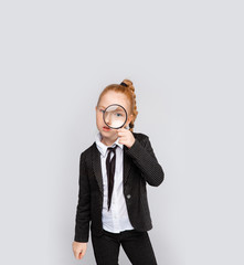red-haired girl in a business suit with a magnifier. Conceptual photo denoting a search for a solution to a problem.