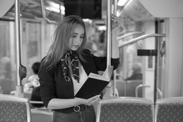 Beautiful young woman in tram reading book