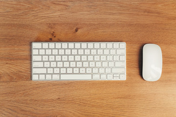 Modern wireless keyboard and mouse on wooden table background. Workplace concept. Top view