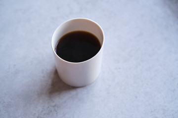 Cup of black coffee in a handmade white ceramics mug, white marble background