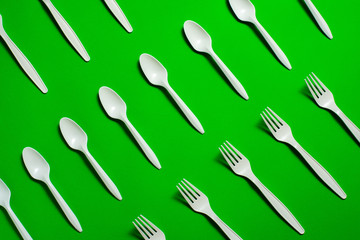 eco-friendly disposable tableware on a green background. isolate. corn starch spoons and forks....