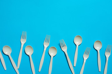 biodegradable disposable forks and spoons of corn starch on a blue background. eco friendly concept. place for text. picnic dishes made of modern materials instead of plastic.