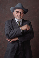 Fototapeta na wymiar Señor maduro posando para la cámara con un traje de color café oscuro con rayas y sombrero