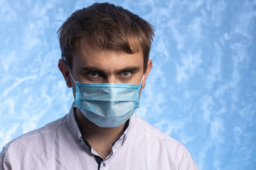 young man in a medical mask. Closeup portrait on a blue background. Hygiene concept. protection against infection during quarantine. place for text