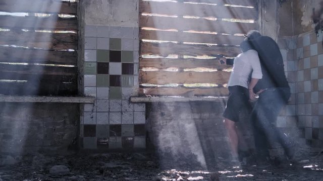 criminal holds hostage by threatening with pistol near window in abandoned building. offender is covered for victim.