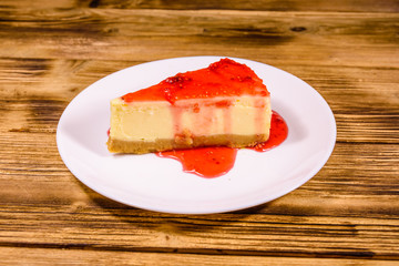 White plate with cheesecake New York and raspberry jam on wooden table