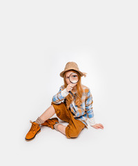 girl explorer in a hat and unmarked clothes for travel sitting on a white background
