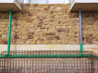 Rostiger Betonstahl vor einer neuen Fassade aus Naturstein in Naturfarben an einer Baustelle in Oerlinghausen bei Bielefeld im Teutoburger Wald in Ostwestfalen-Lippe
