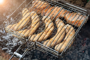 sausages lie on the grill and grilled at the stake. picnic in nature. bright highlight.