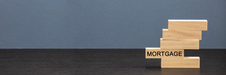 The concept of a mortgage. The financial model of the house with the last piece with the mortgage text.