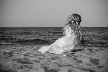 Fototapeta na wymiar little child sitting alone by the sea, princess and fairy concept