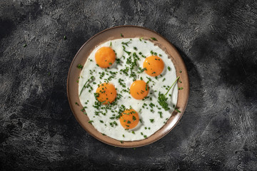 Fried eggs on a ceramic plate with herbs
