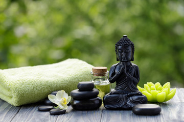 Spa and wellness composition with statuette  of Buddha, oil bottle and zen stones.