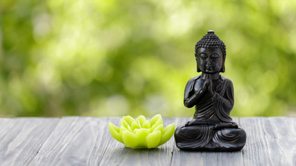 A Buddha statuette and a lotus candle on a wooden board