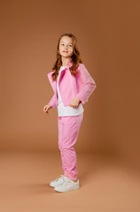 Fototapeta na wymiar little girl in a pink tracksuit on a beige background