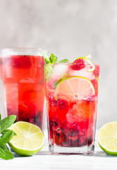 Lemonade or non-alcohol cocktail with raspberry, lime and mint in glass on grey stone background. Summer berry drink.