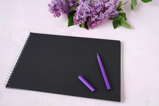 bouquet of lilac flowers and purple pen on a blackboard