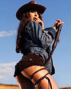 western  cowgirl with a whip in a sheriff hat , touching lips