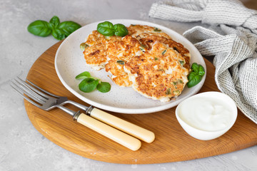 Juicy homemade chicken cutlets on a ceramic plate with basil and sour cream. Light grey concrete background.