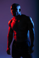 Fototapeta na wymiar Portrait of a professional boxer with a naked torso in a neon light in the studio.