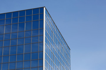 Fototapeta na wymiar Part of a glass mirrored office building reflecting the blue sky.