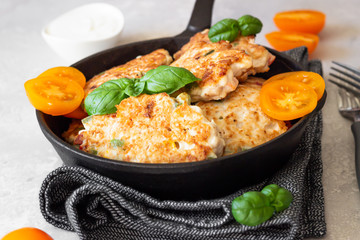Cutlets. Fried delicious chicken or turkey cutlets in cast-iron pan with basil, tomatoes and sauce. Light grey stone background.