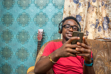 african man making a live video, wearing a headphones, indoors, smiling