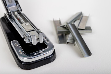 Stapler for fastening sheets of paper and staples. Office accessories for working behind the desk. Light background.