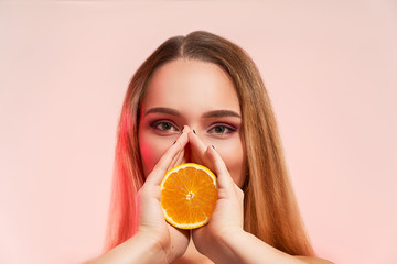 Beautiful girl with orange, isolated on studio background. Cosmetics, food, beauty fashion concept, space for text